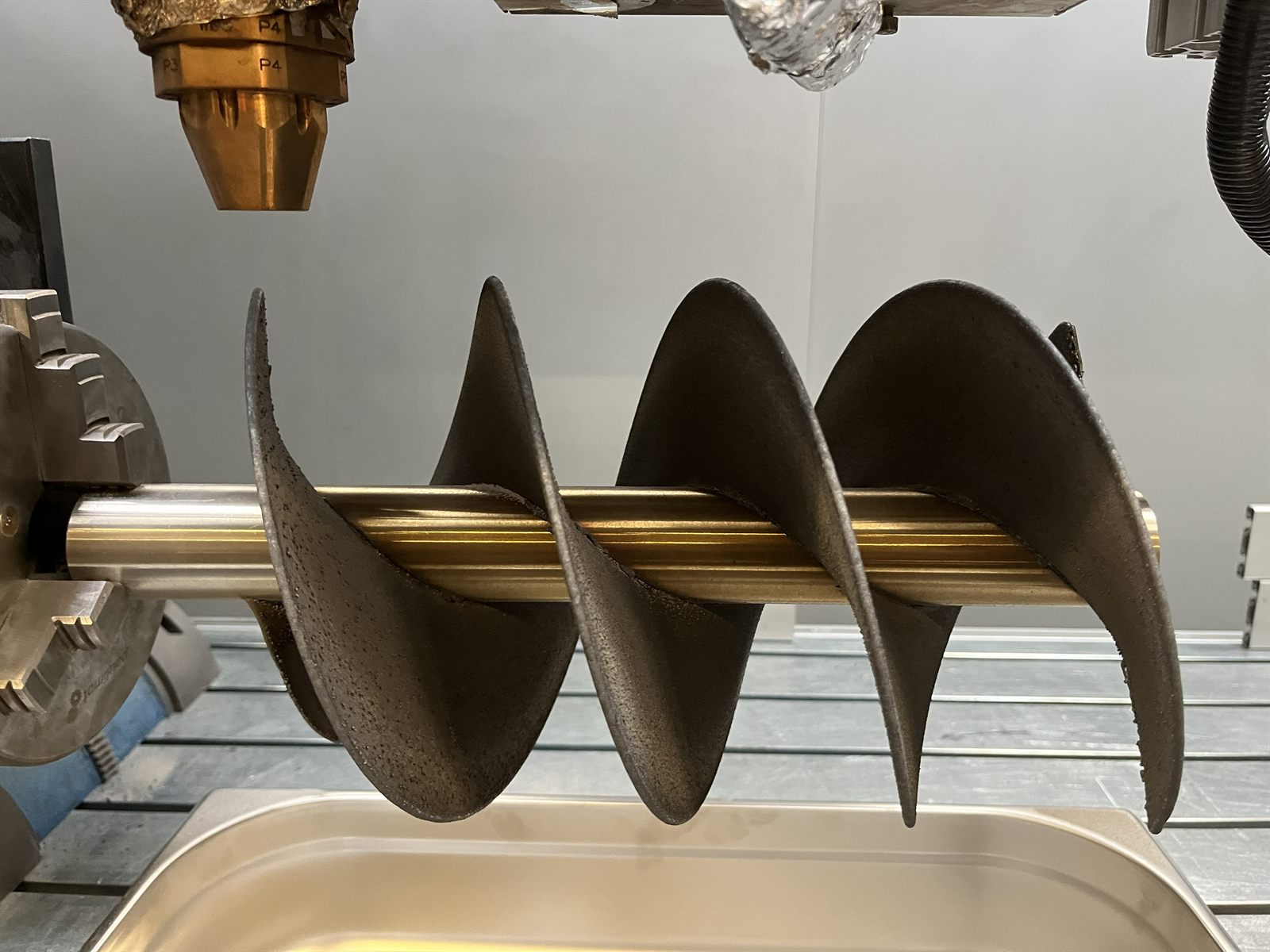 Side view of a metal 3D printed helical impeller prototype showing axial blade pitch and shaft relationship