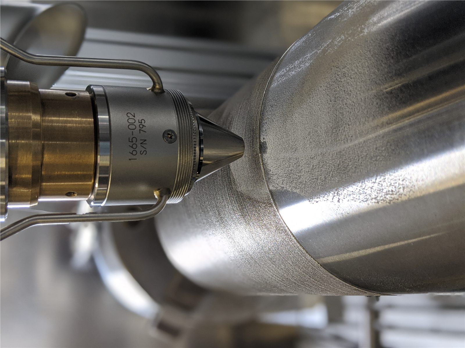 Laser Metal Deposition nozzle above a large cylindrical part during cladding